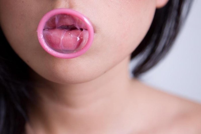 Girl with a condom in her mouth